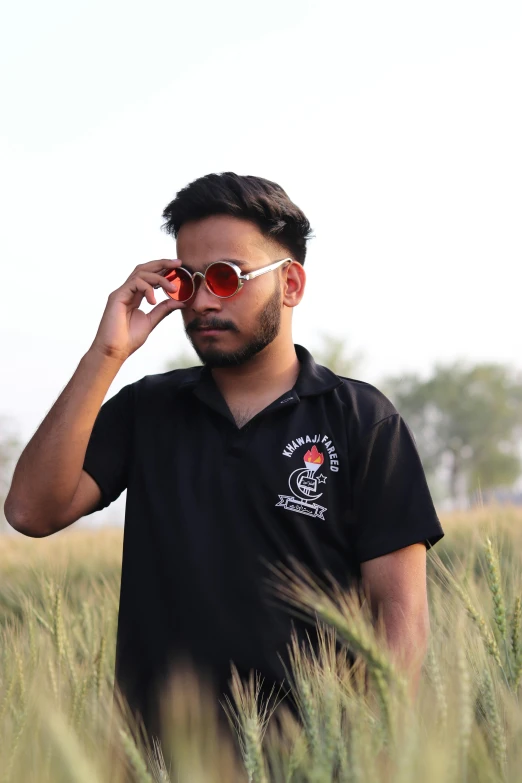 a man standing in a field talking on a cell phone, inspired by Saurabh Jethani, pexels contest winner, realism, wearing shades, wearing a black tshirt, wearing polo shirt, portait photo profile picture