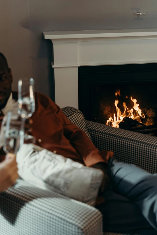 a man sitting on a couch holding a bottle of alcohol, by Carey Morris, pexels contest winner, irori fireplace, lovely couple, bubbly, seasonal