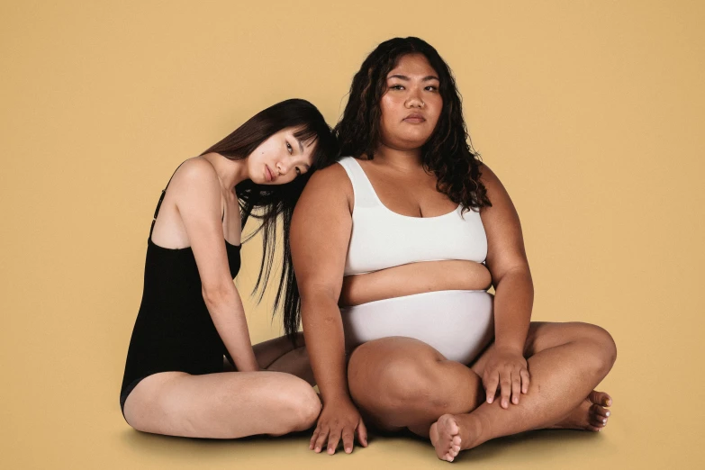 a couple of women sitting next to each other, trending on pexels, realism, her belly is fat and round, ying and yang, tan skin, rubenesque