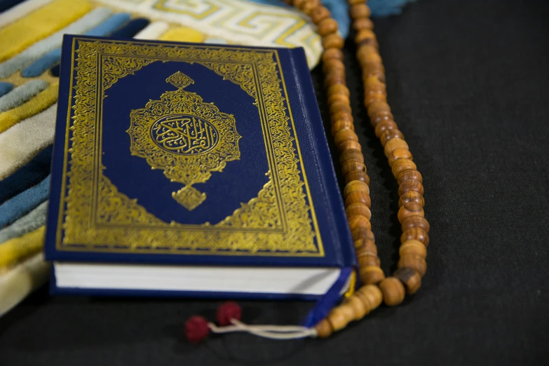 a book sitting on top of a table next to a rosary, hurufiyya, thumbnail, fully decorated, a close up shot