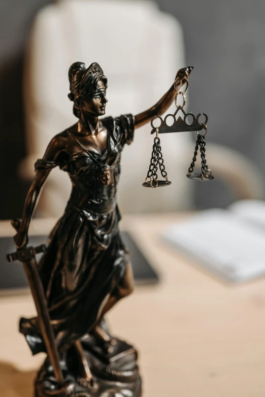 a statue of lady justice holding a scale, a statue, trending on pexels, a high angle shot, looking across the shoulder, on a desk, from the waist up