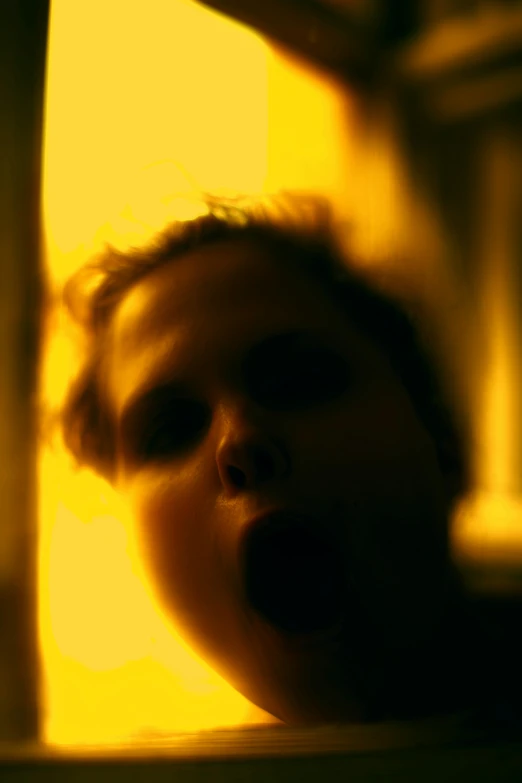 a close up of a child looking out of a window, an album cover, inspired by Gottfried Helnwein, flickr, glowing yellow face, fire from mouth, bathed in golden light, screaming. not realistic