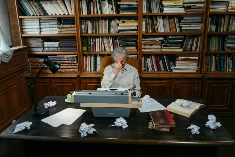 a man sitting at a desk in front of a typewriter, annie liebowitz, a silver haired mad, alessio albi, dusty library