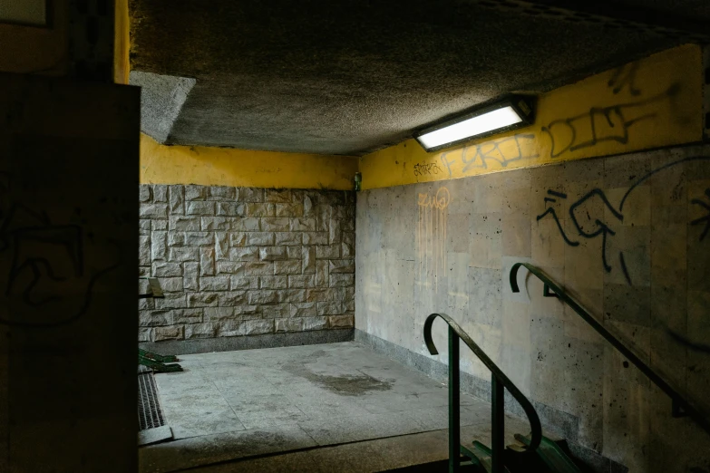 a room with graffiti on the walls and stairs, unsplash, yellow street lights, underground bunker, “gas station photography, an empty brutalist chamber
