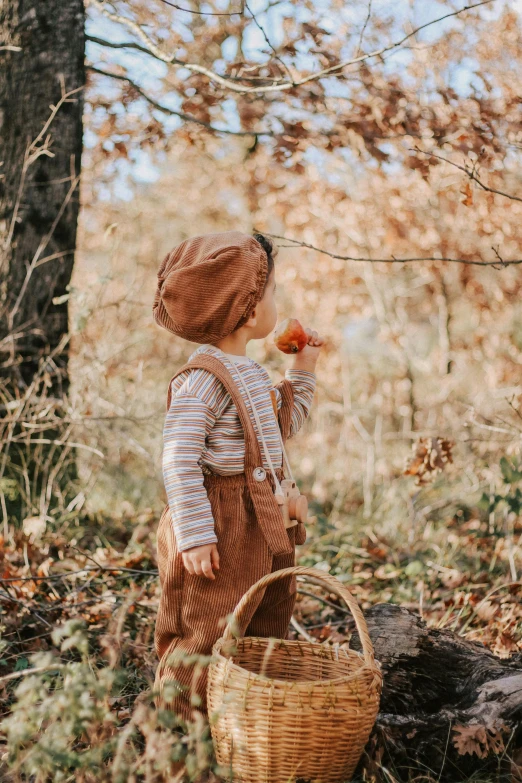 a little boy standing in the woods with a basket, inspired by Elsa Beskow, pexels contest winner, fine art, orange jumpsuit, 🍁 cute, muted browns, profile pic