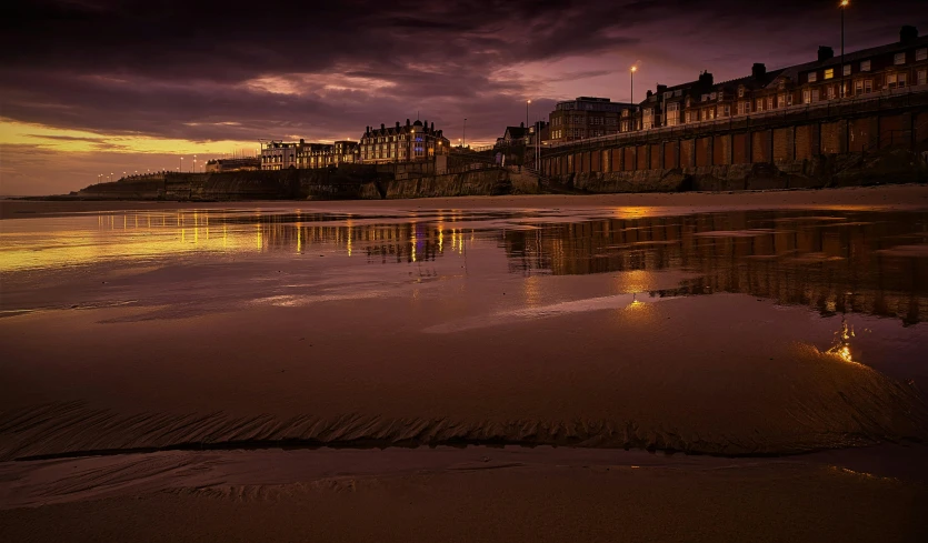 a couple of buildings sitting on top of a sandy beach, by Andrew Geddes, pexels contest winner, baroque, evening lighting, marsden, lit from bottom, seaside backgroud