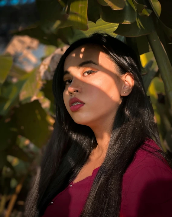 a woman with long black hair standing under a tree, inspired by Ruth Jên, unsplash, sumatraism, non binary model, sunny lighting, portait photo, trending photo