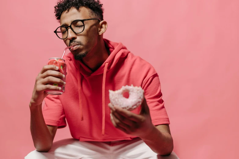 a man sitting on a stool eating a donut, trending on pexels, pink glasses, juice, man is with black skin, candy treatments