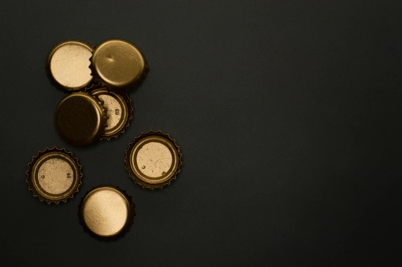 a bunch of bottle caps sitting on top of a table, by Zoltán Joó, pexels contest winner, black gold color scheme, minimalist, liquid gold, panel