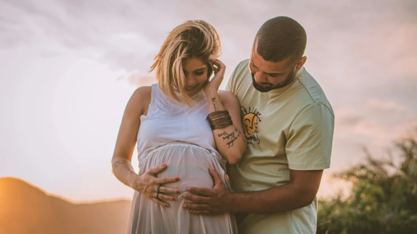 a man and a woman standing next to each other, pexels contest winner, symbolism, pregnant, photograph of a sleeve tattoo, ad image, coloured photo