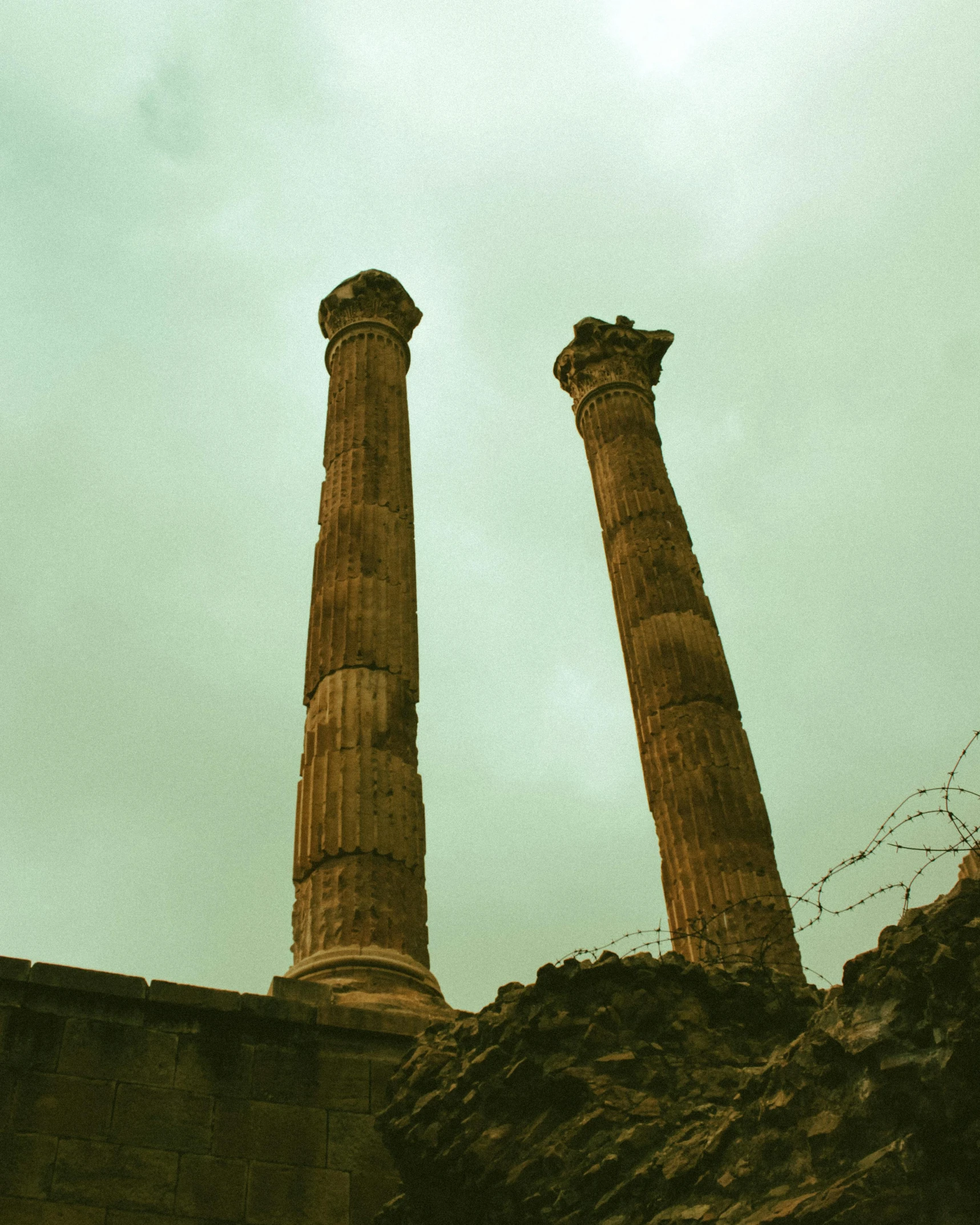 a couple of tall pillars sitting next to each other, an album cover, unsplash contest winner, romanesque, pompeii, trending on vsco, citadel of erbil, wrecked buildings