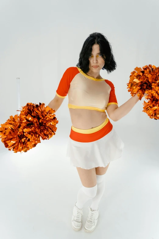 a woman in a cheerleader outfit holding two pom poms, an album cover, inspired by Bert Stern, featured on reddit, white and orange breastplate, kiko mizuhara, finn wolfhard, studio photoshoot