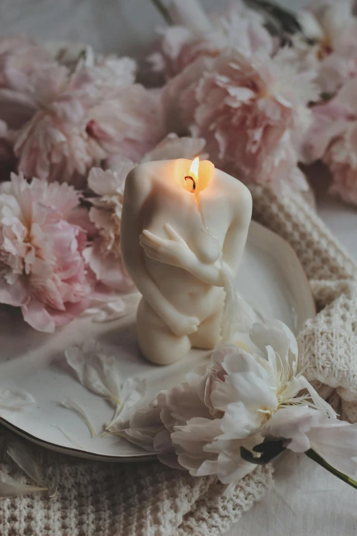 a white candle sitting on top of a white plate, a marble sculpture, inspired by Elsa Bleda, romanticism, loving embrace, flowers growing out of his body, albino mystic, soft lights