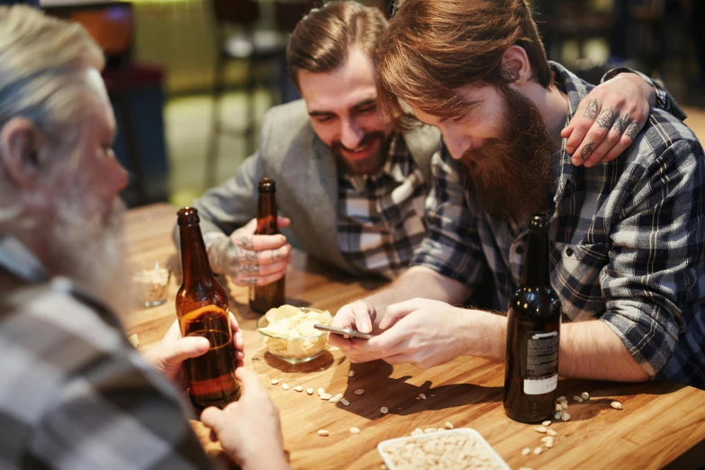 a couple of men that are sitting at a table, by Joe Bowler, pexels, holding a bottle of beer, playing games, bearded, instagram post