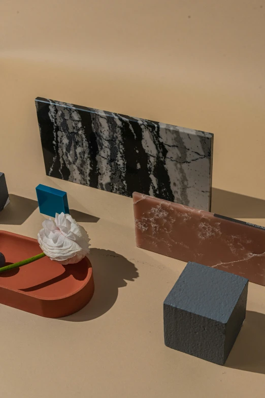 a group of objects sitting on top of a table, an abstract sculpture, by Harvey Quaytman, unsplash, modernism, colored marble, low - relief stone sculpture, flowers, black marble