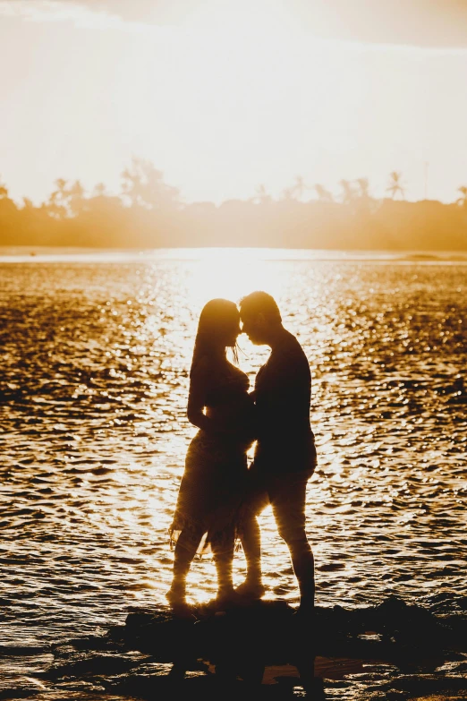 a couple kissing in front of a body of water, on the beach during sunset, standing next to water, siluettes, morning lighting