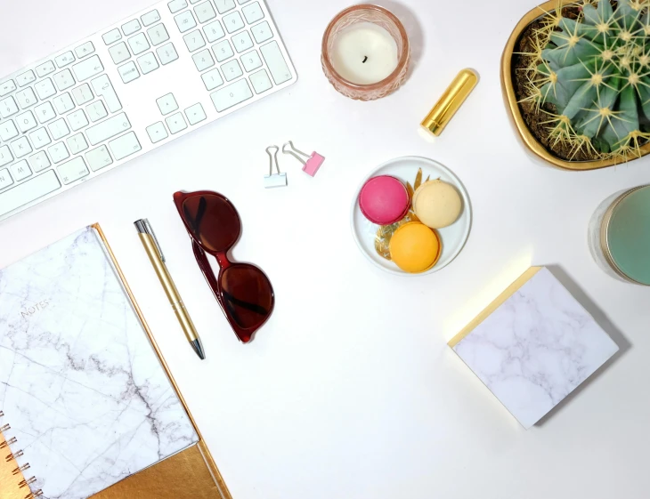 a white desk topped with a keyboard and a cup of coffee, a still life, inspired by Eden Box, trending on pexels, yellow carrera glasses, pink marble building, snacks, with a white background