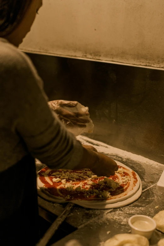 a woman making a pizza in a kitchen, a picture, by Matt Cavotta, trending on unsplash, made of glazed, close - up photograph, daily specials, grainy photo