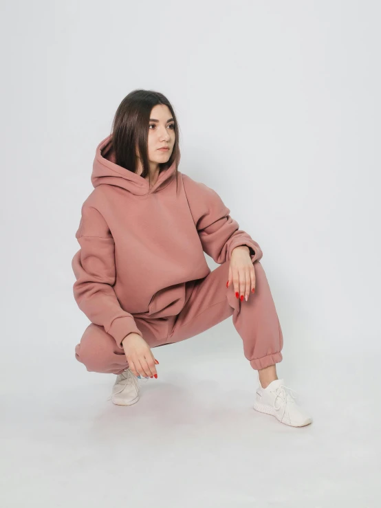 a woman in a pink hoodie crouching down, by Matija Jama, trending on pexels, high waist sweatpants, better known as amouranth, muted brown, detailed product photo