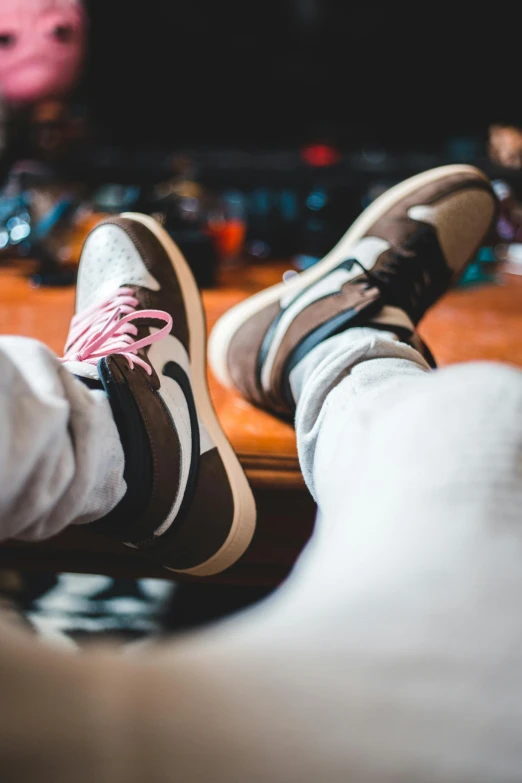 a person sitting on a couch with their feet up, an album cover, inspired by Jordan Grimmer, trending on pexels, focus on sneakers only, “air jordan 1, muted brown, close up high detailed