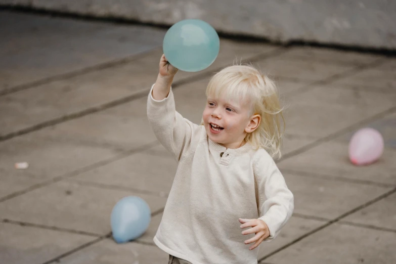 a little girl holding a blue frisbee in her hand, by Emma Andijewska, pexels contest winner, happening, man holding a balloon, blond boy, happy intricate, floating. greenish blue