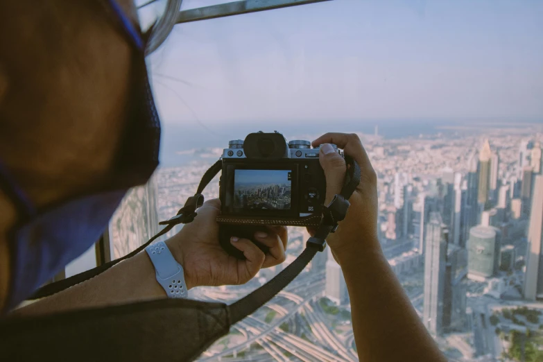 a man taking a picture of a city with a camera, a picture, pexels contest winner, view from helicopter, towering over your view, youtube thumbnail, helmet view