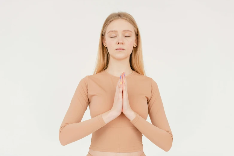 a woman sitting in a yoga position with her eyes closed, trending on pexels, aestheticism, brown clothes, prayer hands, portrait of kim petras, standing posture