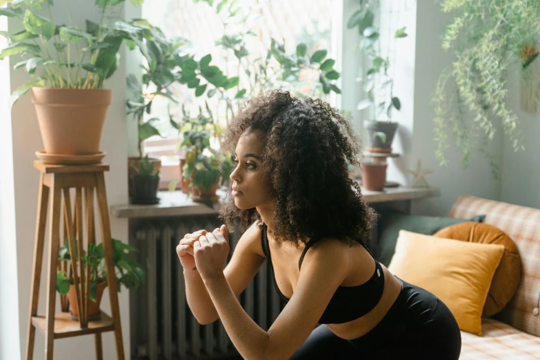 a woman sitting on a couch in a living room, trending on pexels, cottagecore!! fitness body, with afro, profile image, kneeling