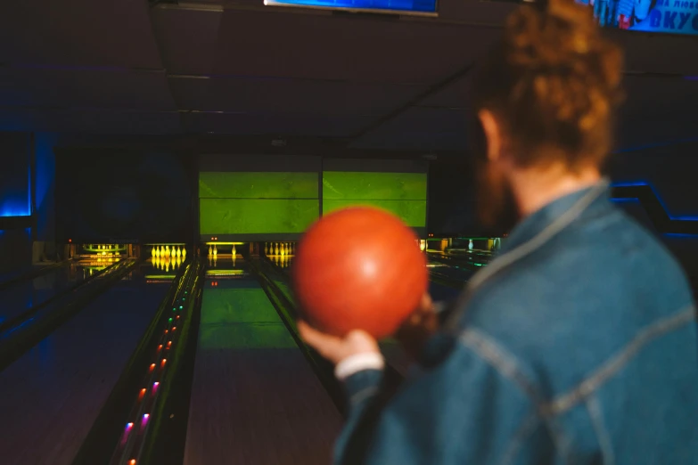 a man holding a bowling ball in a bowling alley, unsplash, colour photograph, facing away, evening time, lane brown