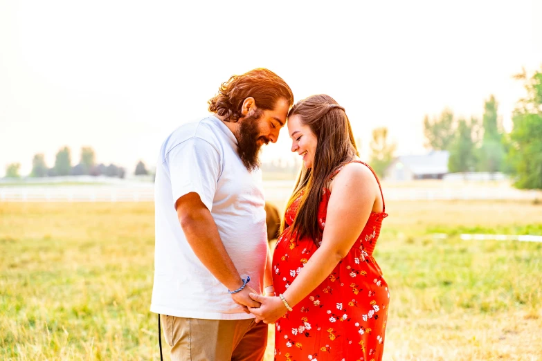 a man and woman standing next to each other in a field, pexels contest winner, pregnant belly, avatar image, beard, profile image