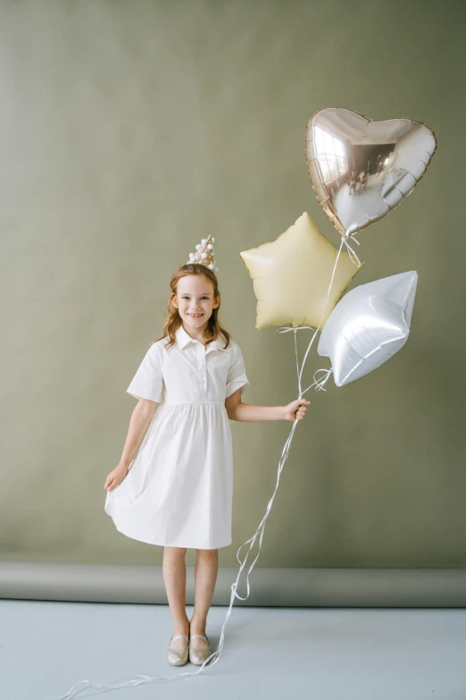 a little girl holding a bunch of balloons, inspired by Elsa Beskow, silver white and gold, school uniform, product shot, crown