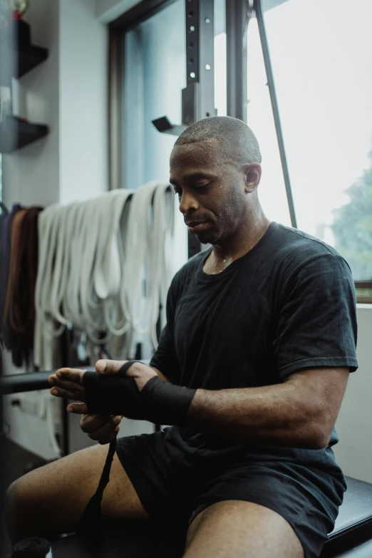 a man sitting on a bench in a gym, profile image, malcolm hart, he is holding a smartphone, ignant