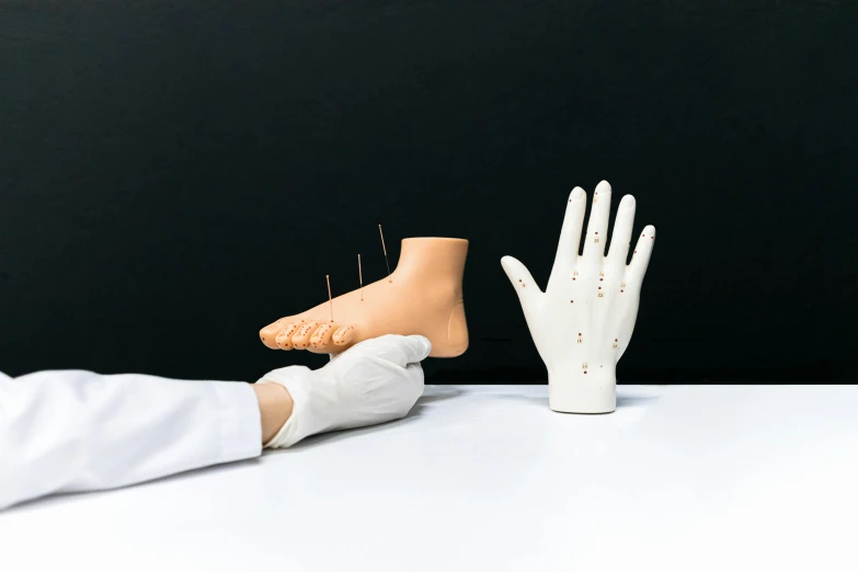 a close up of a person with a glove on, a surrealist sculpture, unsplash, hyperrealism, acupuncture treatment, the forefoot to make a v gesture, wearing lab coat and a blouse, hand on table