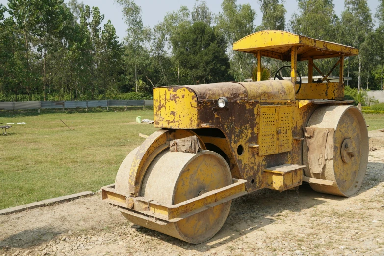 a large yellow machine sitting on top of a dirt field, bengal school of art, restoration, tar roads, promo image, bangladesh