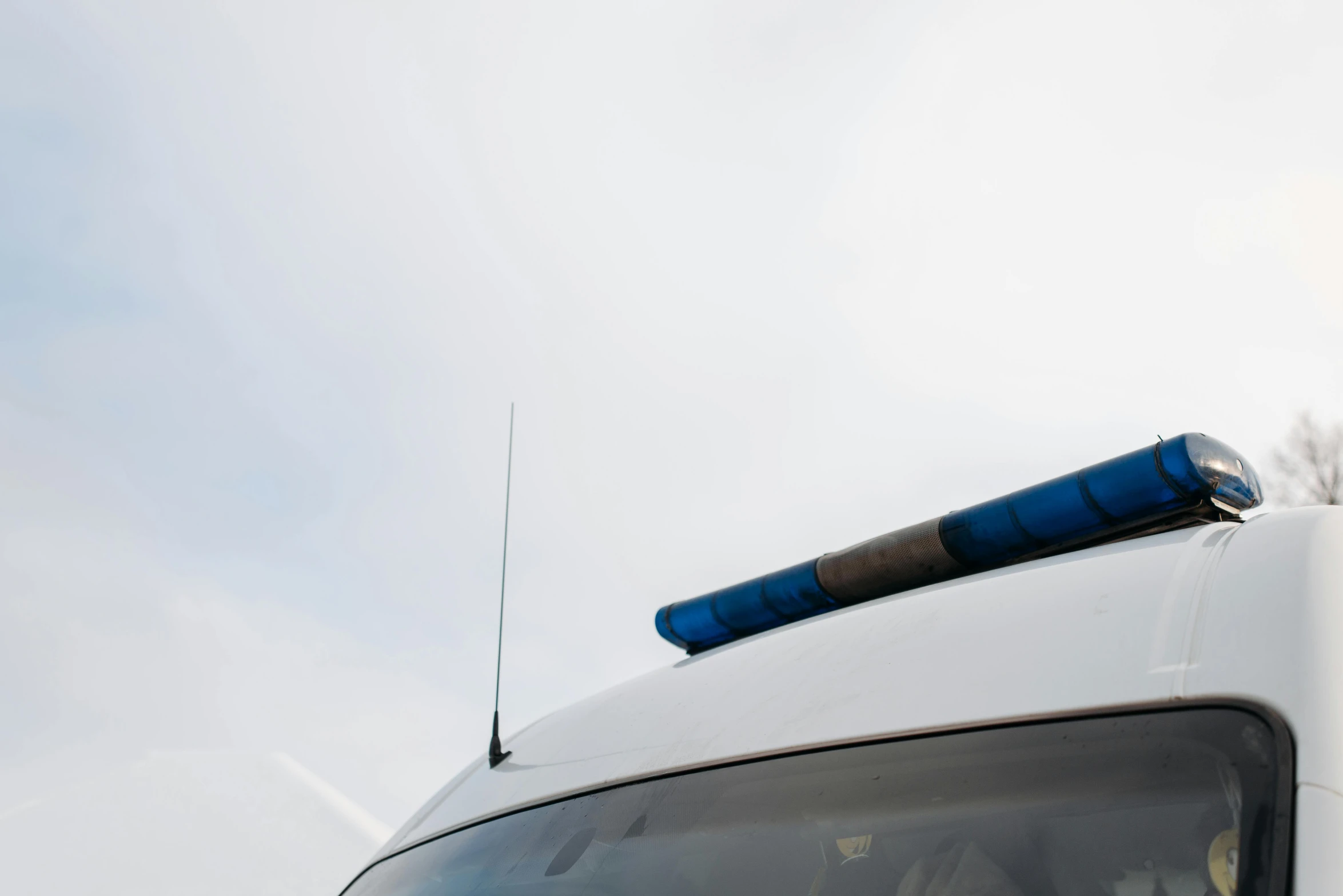 a white van with a blue light on top of it, unsplash, private press, policeman closeup, white sky, dipstick tail, high quality photo