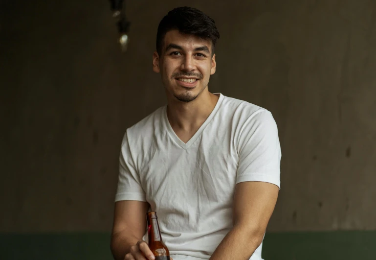 a man in a white shirt holding a bottle of beer, a portrait, pexels contest winner, nathan for you, enes dirig, smiling male, khyzyl saleem