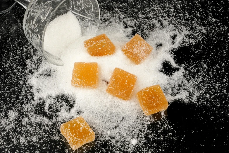 sugar and sugar cubes on a table, inspired by Kanō Shōsenin, unsplash, renaissance, jelly - like texture. photograph, square, on a black background, fluffy orange skin