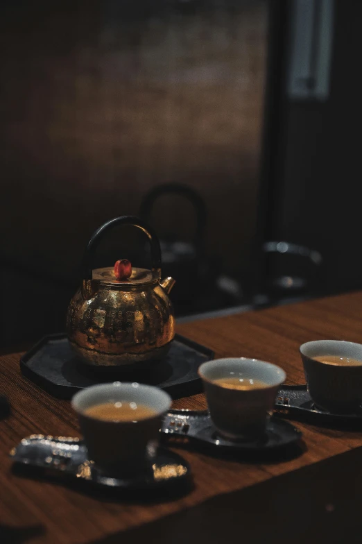 a tea pot sitting on top of a wooden table, inspired by Kanō Shōsenin, trending on unsplash, mingei, low quality photo, thumbnail, dessert, gold