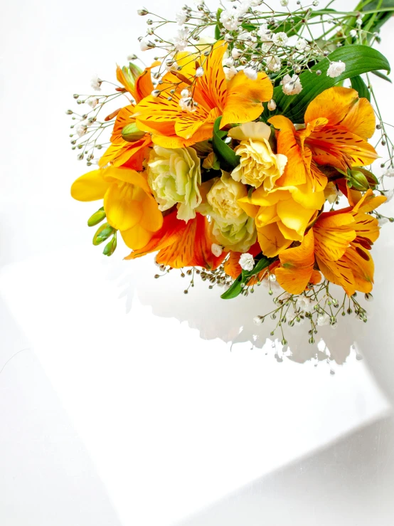 a bouquet of orange and yellow flowers on a white surface, an album cover, greeting card, product display photograph, sunlight, square