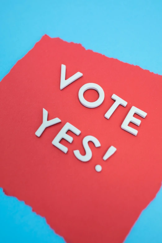 a red piece of paper with the words vote yes on it, by Carey Morris, shutterstock contest winner, adafruit, pastel', blue, aerial