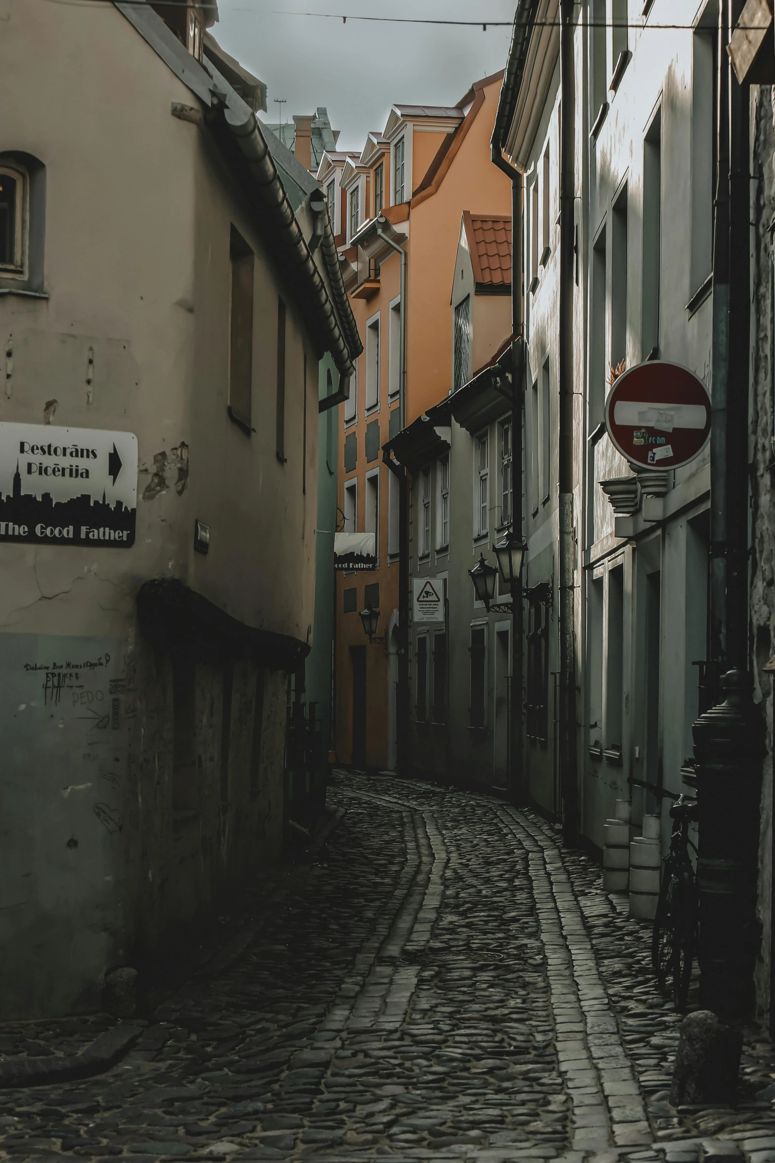 a cobblestone street in an old european city, a picture, pexels contest winner, graffiti, muted colors, tallinn, street signs, low quality photo