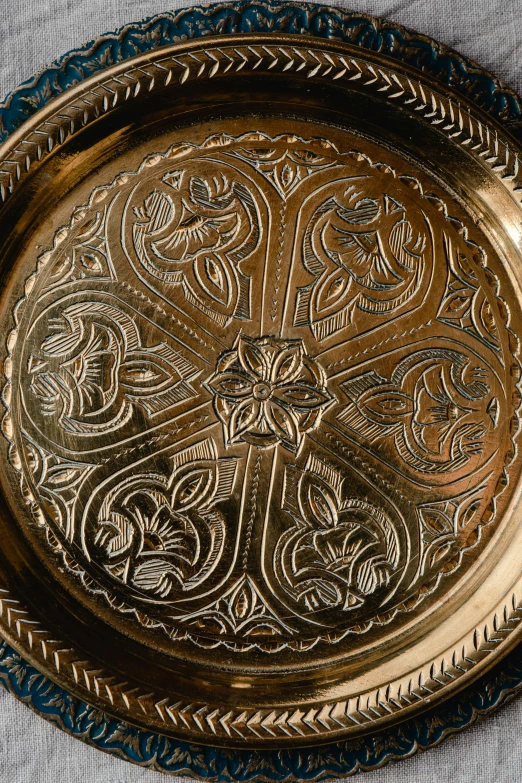 a close up of a metal plate on a table, inspired by Aladár Körösfői-Kriesch, trending on unsplash, arabesque, made of bronze, oman, medium detail, detailed product shot