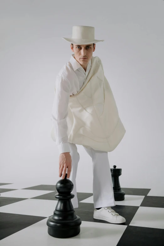 a man standing on top of a chess board, an album cover, inspired by Horace Vernet, unsplash, bauhaus, in a flowing white tailcoat, avant garde fashion model, wearing a linen shirt, non binary model