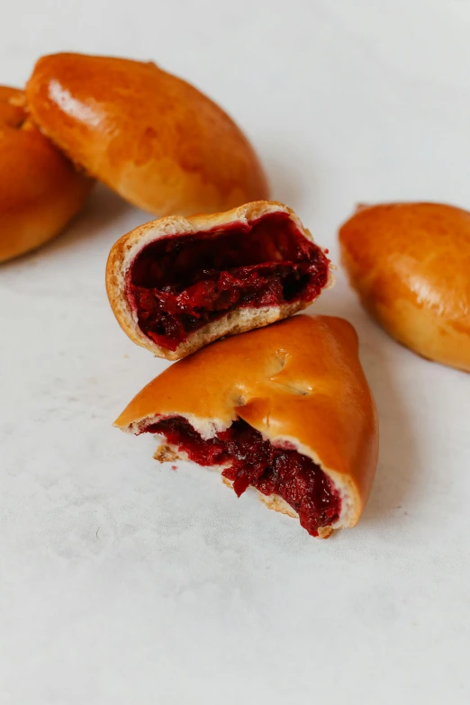 a couple of doughnuts sitting on top of a table, maroon red, split in half, polish food, 3 - piece