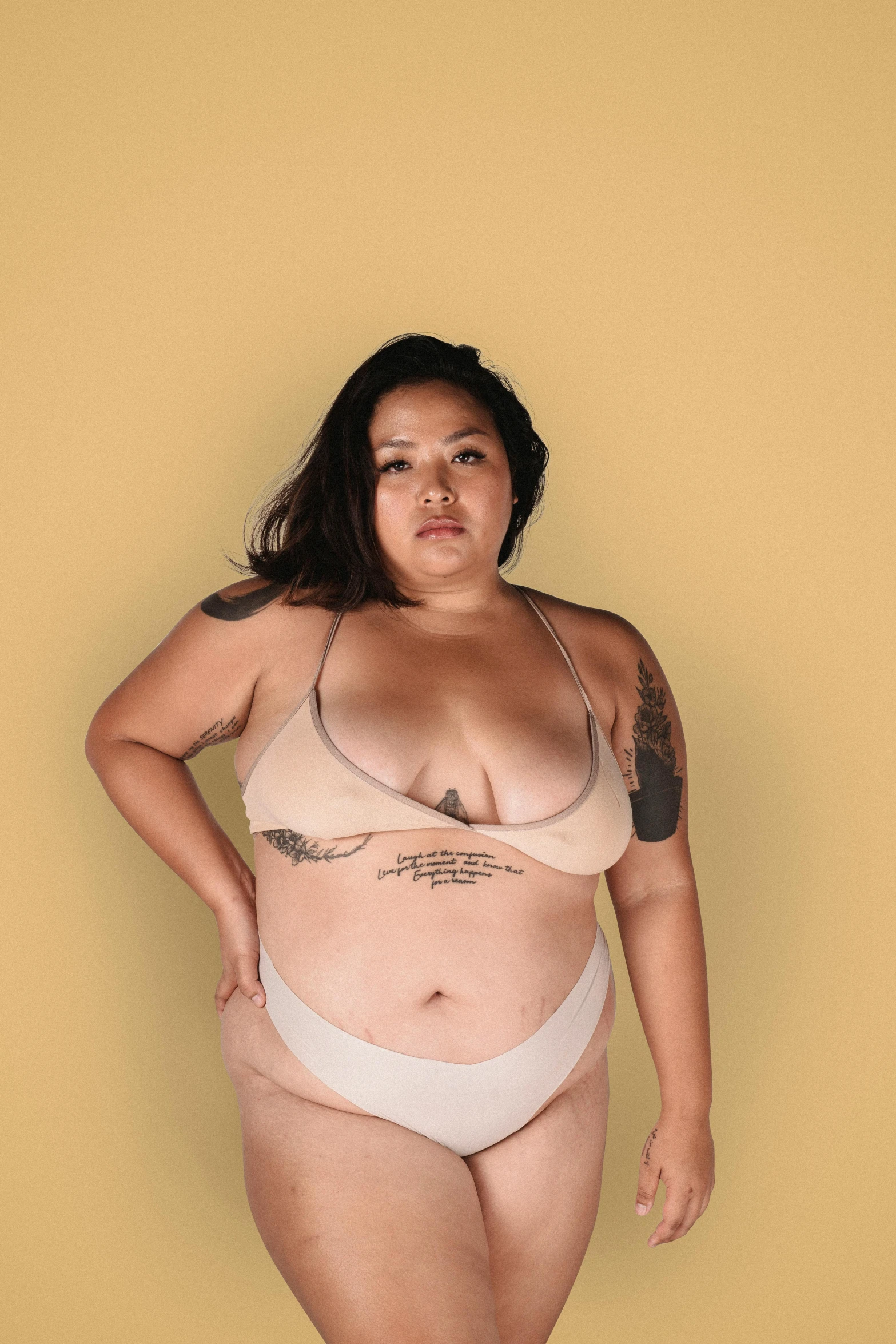 a woman in a bikini posing for a picture, an album cover, inspired by Ren Hang, trending on pexels, bbw, nonbinary model, half asian, solid background