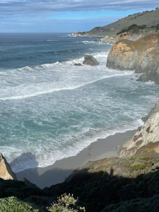 a view of the ocean from the top of a hill, large waves hitting the cliff, profile image