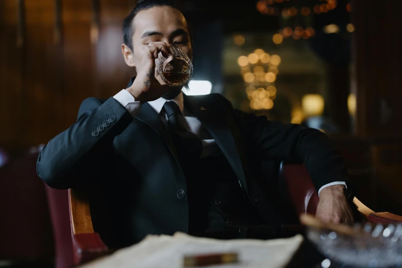 a man sitting at a table with a donut in his mouth, inspired by William Grant Stevenson, pexels contest winner, renaissance, black tie, drinking a glass of whiskey, asian man, chillin at the club together