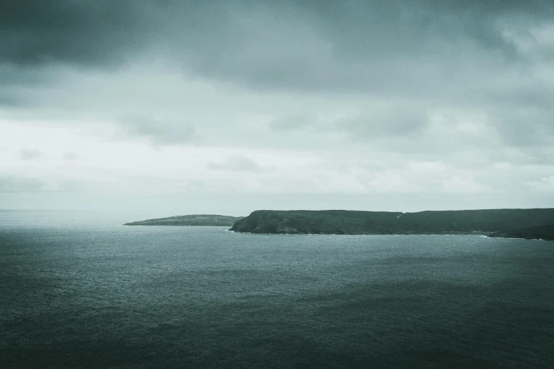 a large body of water under a cloudy sky, pexels contest winner, minimalism, pembrokeshire, hestiasula head, desaturated blue, dreary