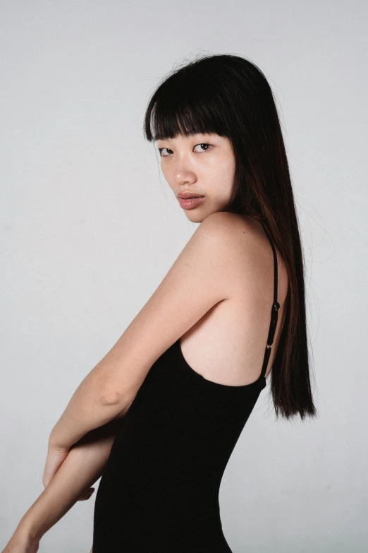 a woman in a black dress posing for a picture, an album cover, inspired by Kim Tschang Yeul, pexels contest winner, realism, wearing : tanktop, young asian girl, hair blackbangs hair, thin aged 2 5