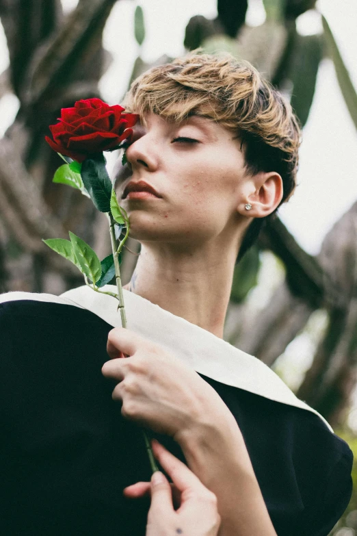 a woman holding a rose in front of her face, an album cover, inspired by Hedi Xandt, unsplash, romanticism, teen boy, wearing an academic gown, androgynous male, portrait of max caulfield